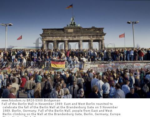 Fall of the Berlin Wall in November 1989: East and West Berlin reunited to celebrate the fall of the Berlin Wall at the Brandenburg Gate on 9 November 1989. Berlin, Germany. Fall of the Berlin Wall, people from East and West Berlin climbing on the Wall at the Brandenburg Gate, Berlin, Germany, Europe Photo Norbert Michalke