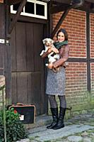 Brunette woman in scarf holding dog in arms and st