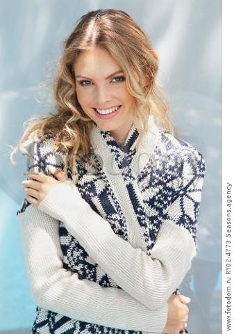 A young blonde woman wrapped in a blue-and-white knitted cardigan