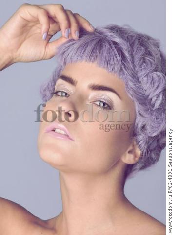 A young woman with pastel coloured make up wearing a short purple wig