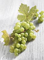 Green grapes on a wooden background with vine leav