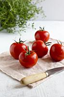 Whole tomatoes on white surface with fresh thyme a