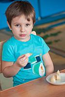 Мальчик кушает за столом в детском саду