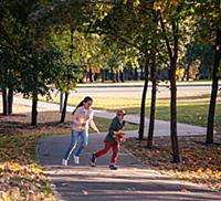 Мальчик и девочка гуляют в парке осенью в солнечны