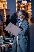Девушка в сером пальто с книгой в руках на улице г