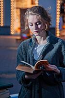 Девушка в сером пальто с книгой в руках на улице г